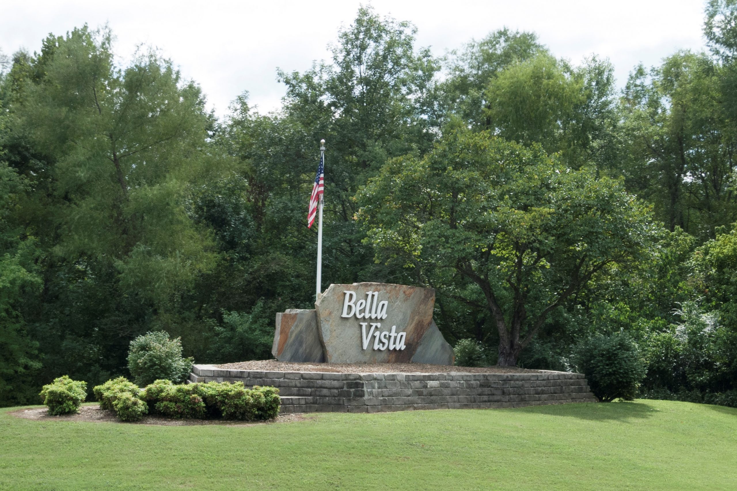 Bella Vista, Arkansas in Northwest Arkansas welcome sign with American Flag and formal landscaping.