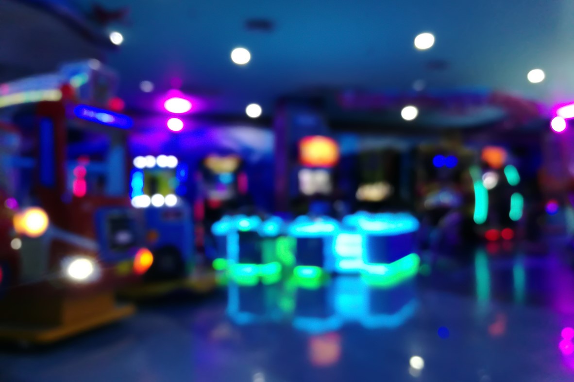 blurred arcade machine game for children game play  in department store. Playground with colorful neon lights and bokeh light. Colorful absract background.