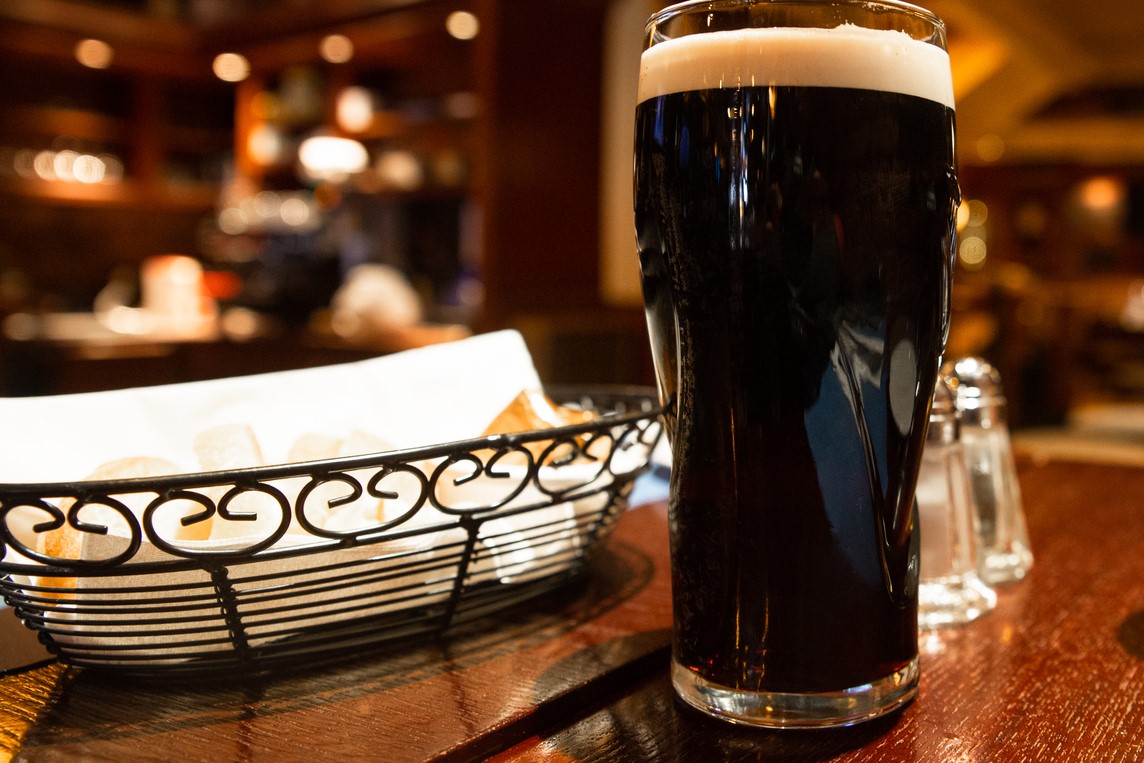 Glass of dark beer on a table in a pub setting